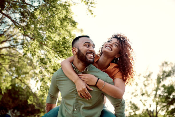 Shot of young couple, man giving piggy back ride to lady. They are both smiling after selling a home they couldn't afford the payments on. They were going to foreclose but they sold to a cash home buyer.