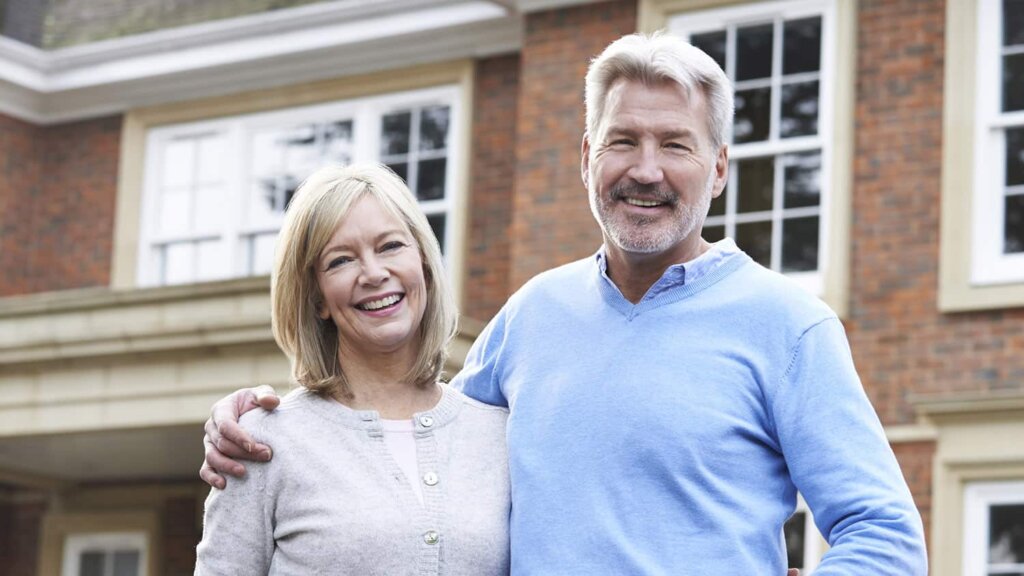 Middle aged couple standing in front of the rental property that they sold to an investor in Sealy, Texas. They had a tenant that was late on payment and had destroyed the house. They sold to an investor and left the property as is.