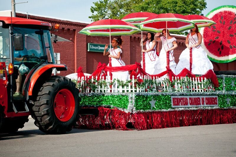 Picture of a tractor pulling a float in a parade at the watermelon festival in Hempstead, Texas. J&A Home Buyers are familiar with local traditions in Hempstead, Texas.