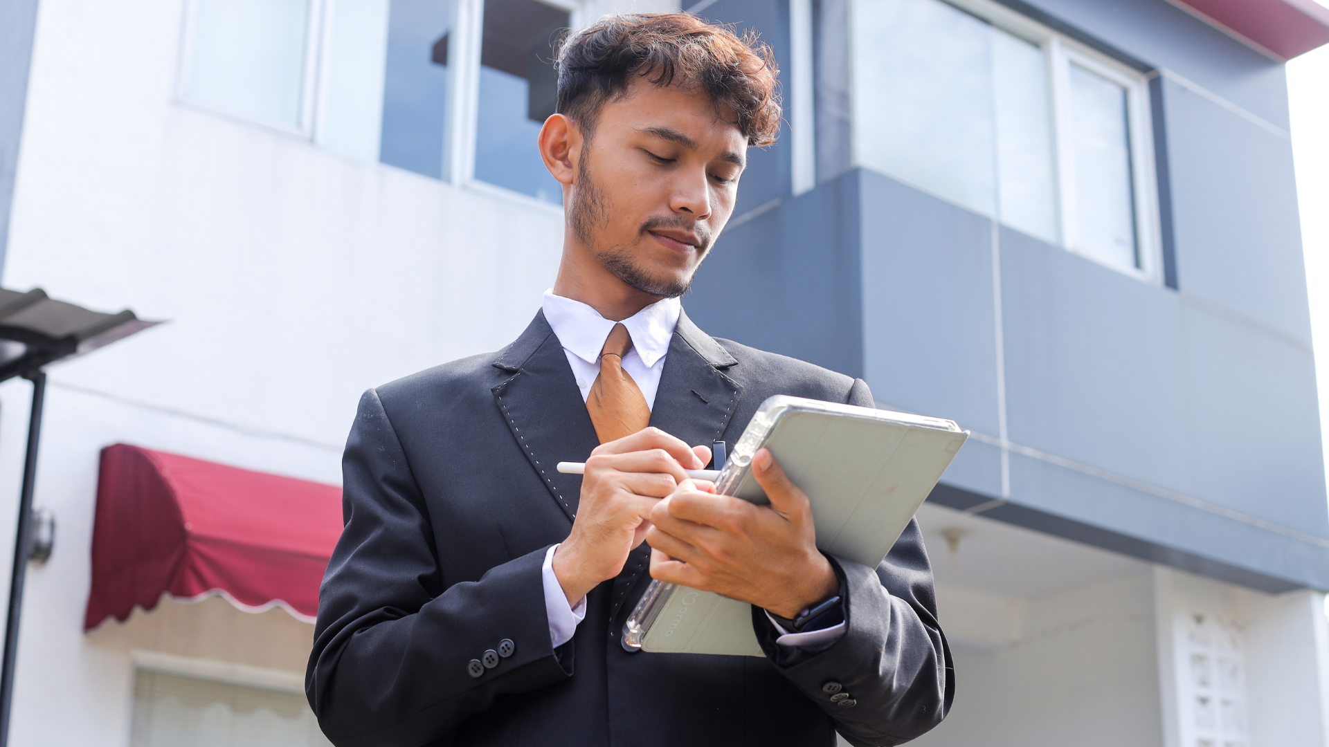 Short-term rental property manager conducting exterior inspection using a tablet.