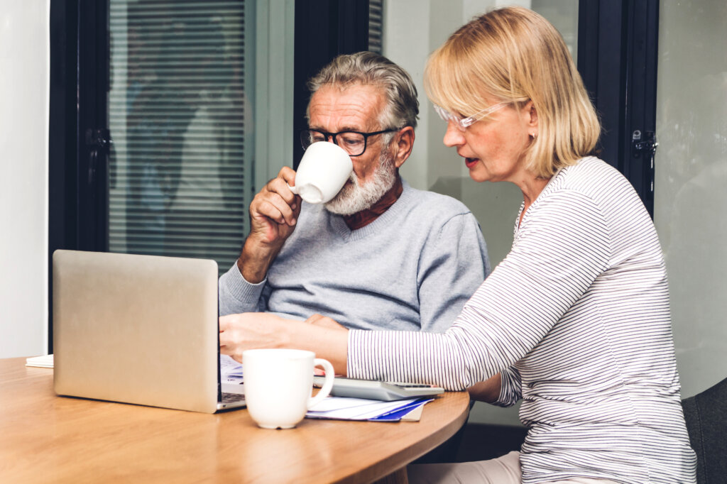 Senior couple reading documents and calculating bills to pay in