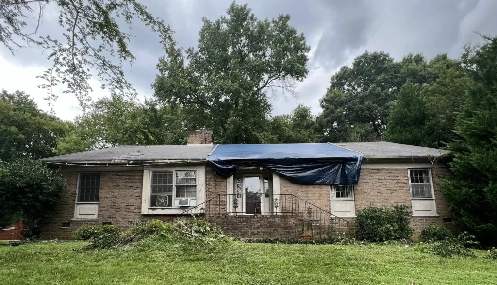 Brick ranch home in Charlotte, NC with broken roof from tree damage needs roof repair and renovation.