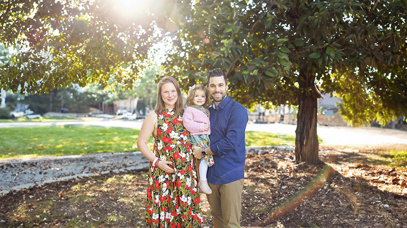 Young white husband and wife smiling at christ community church on easter sunday with the daughter