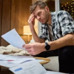 Stressed homeowner reviewing foreclosure documents in Oregon home