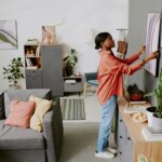This image shows someone placing a piece of art on their wall, demonstrating one way to stage a home.