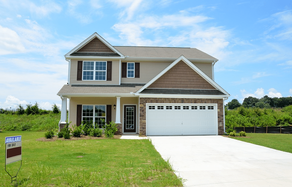 Two-story suburban home for sale in Crystal Lake, IL with a "Available" yard sign, blue sky, and a well-kept front lawn.