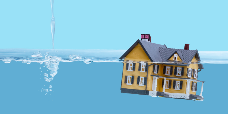 A house model with for-sale sign floating on water