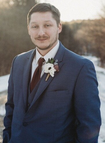 man in suit outdoors with sun in background
