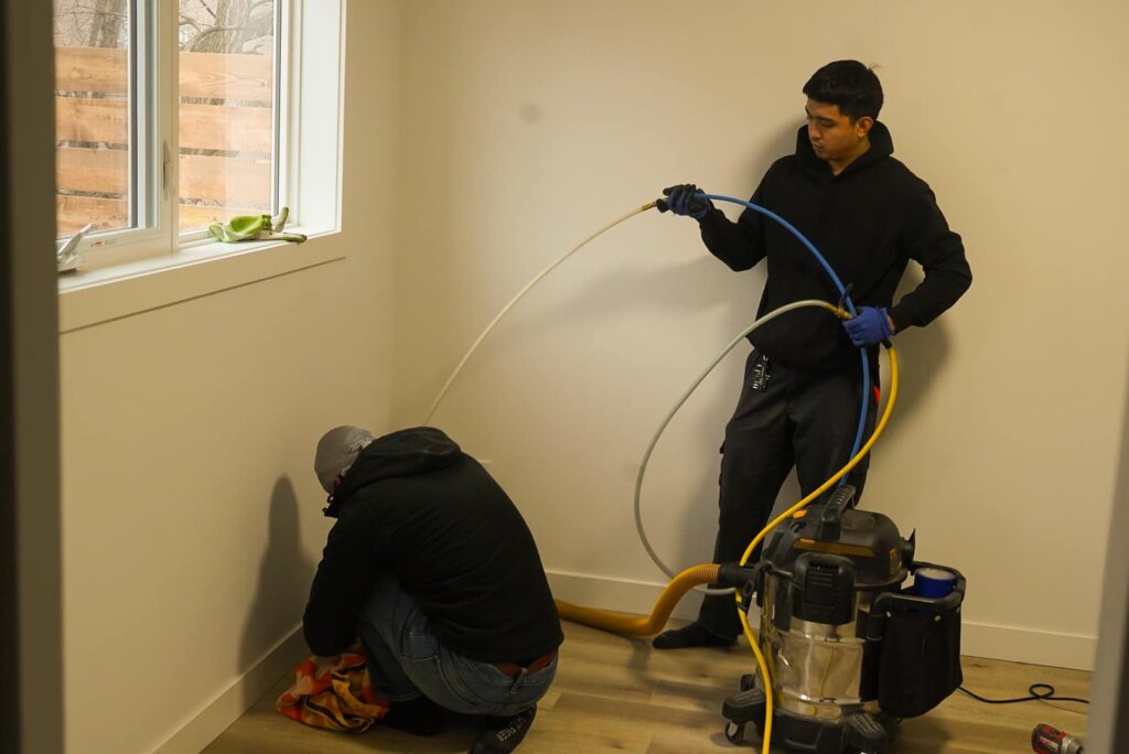 two workers using vacuum cleaner for air duct cleaning calgary