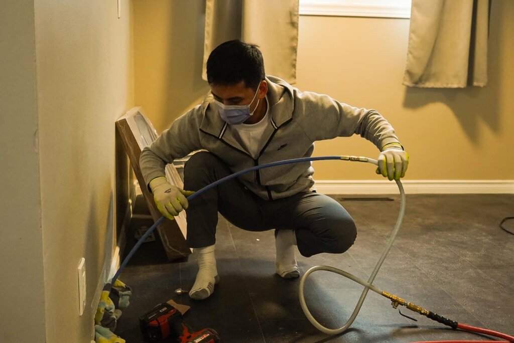 duct cleaning Calgary A man using a hose to clean a room