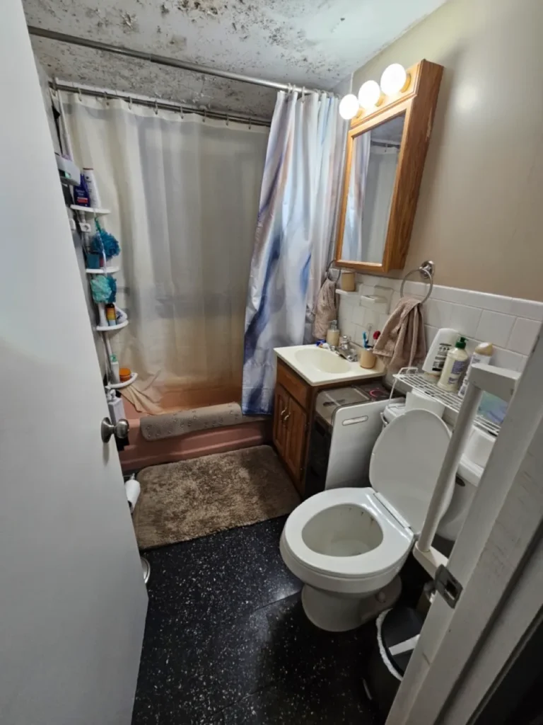 Outdated bathroom in an inherited Worcester house showing ceiling water damage and mold issues.