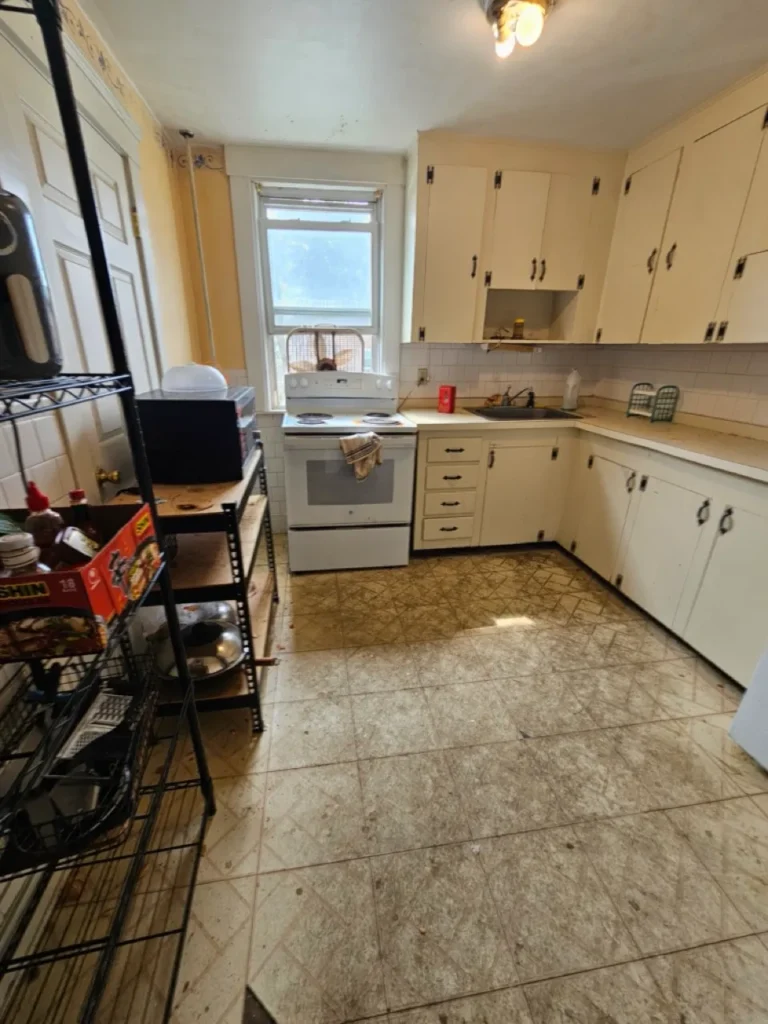 Outdated residential kitchen with stained flooring and worn cabinets in an inherited Worcester home.