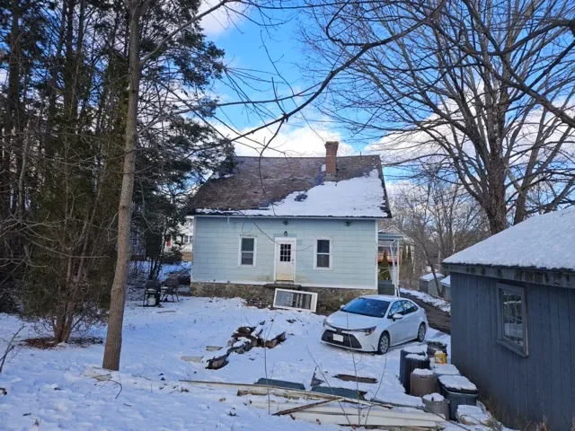 Older blue single-family house in Southbridge MA with snow on the roof and deferred exterior maintenance.