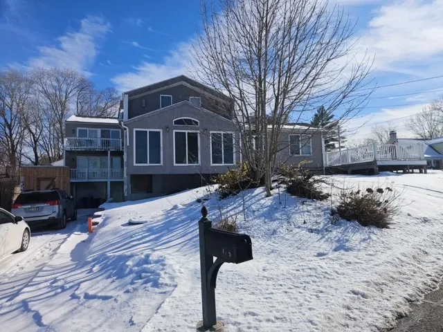 Snow-covered inherited family home in Massachusetts with a large front yard and deck, bought by local home buyers.