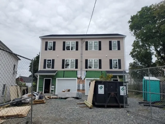 Multifamily home under construction with dumpster in Worcester Massachusetts, purchased as-is by cash home buyer.