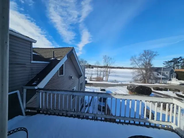 Scenic winter view of a frozen lake from the second-story wooden deck of a Worcester home