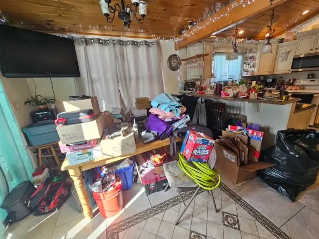 Cluttered kitchen and dining area inside a Killdeer Island home with packed boxes and furniture