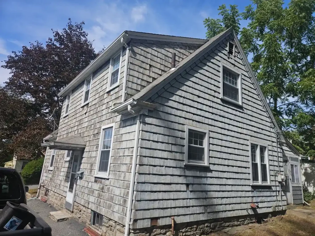 Exterior view of an Oxford rental house featuring weathered wood shingle siding and windows needing updates