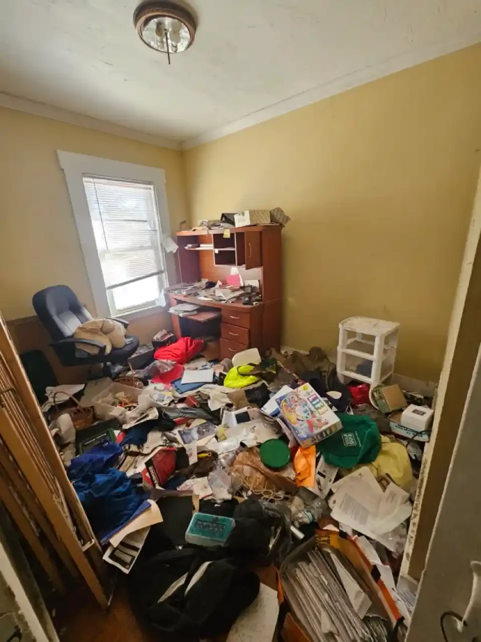 Small bedroom in a property with accumulated belongings, scattered paperwork, and a cluttered floor