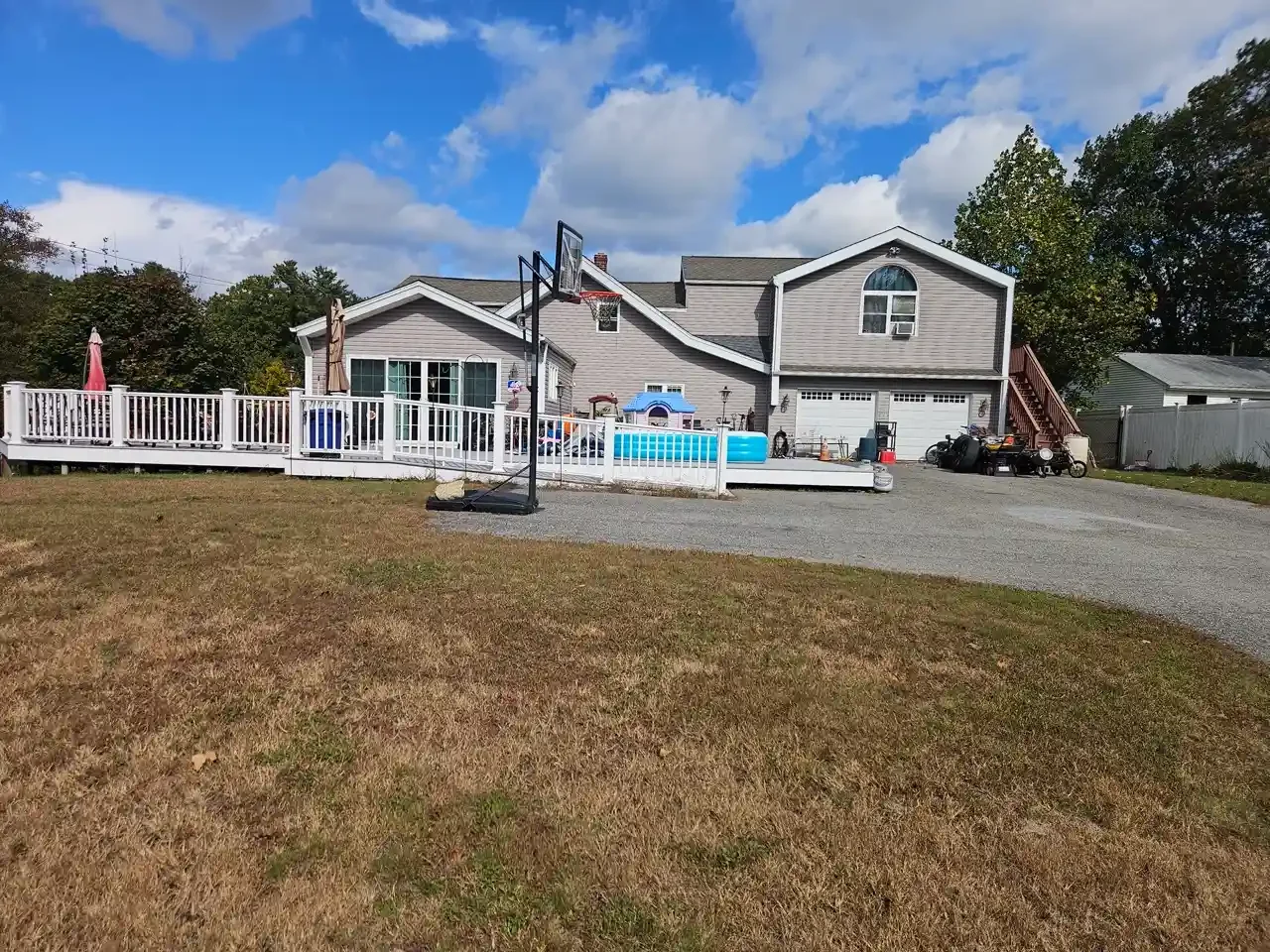 Rear exterior view of a Greater Boston rental property featuring a large wooden deck and backyard