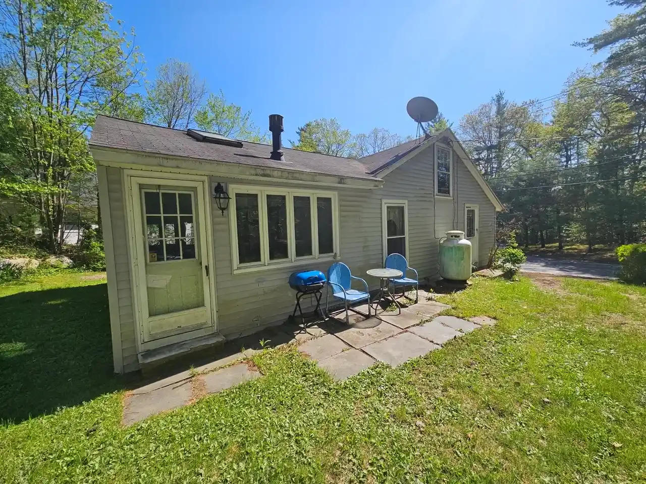Exterior view of a small single-story rental property in Greater Boston with a patio and outdoor seating