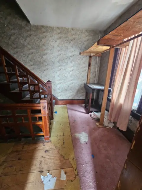 Hallway with severely damaged subflooring and stained carpeting, requiring full replacement.