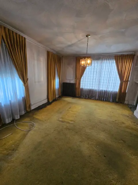 Large empty room with old yellow carpet that requires complete replacement.