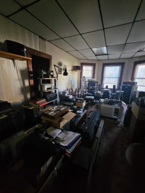 Living space with cluttered belongings and walls needing repairs