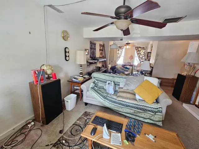 Living room with a sofa, coffee table, large speakers, loose electrical and other things.