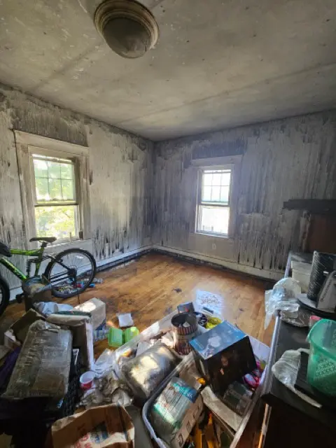 Room with heavily worn walls and a cluttered floor that requires complete repair.