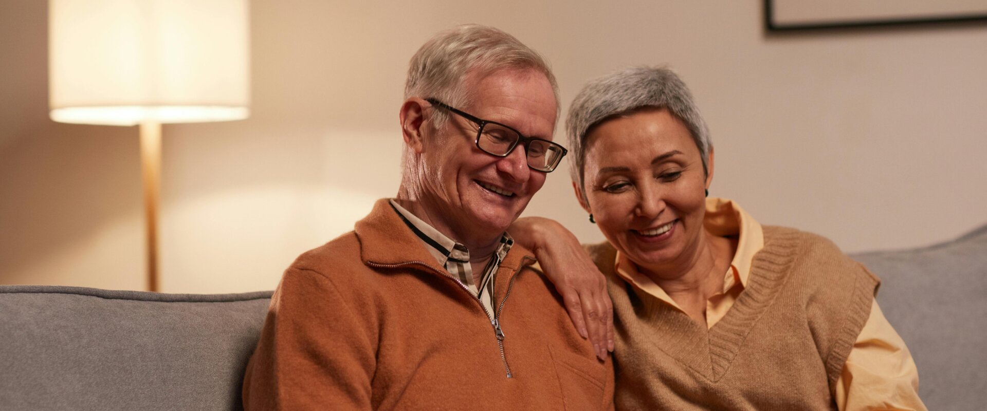 Smiling older couple sitting on a couch looking at a laptop together regarding Unclaimed Money Maryland Unclaimed Funds Surplus Funds