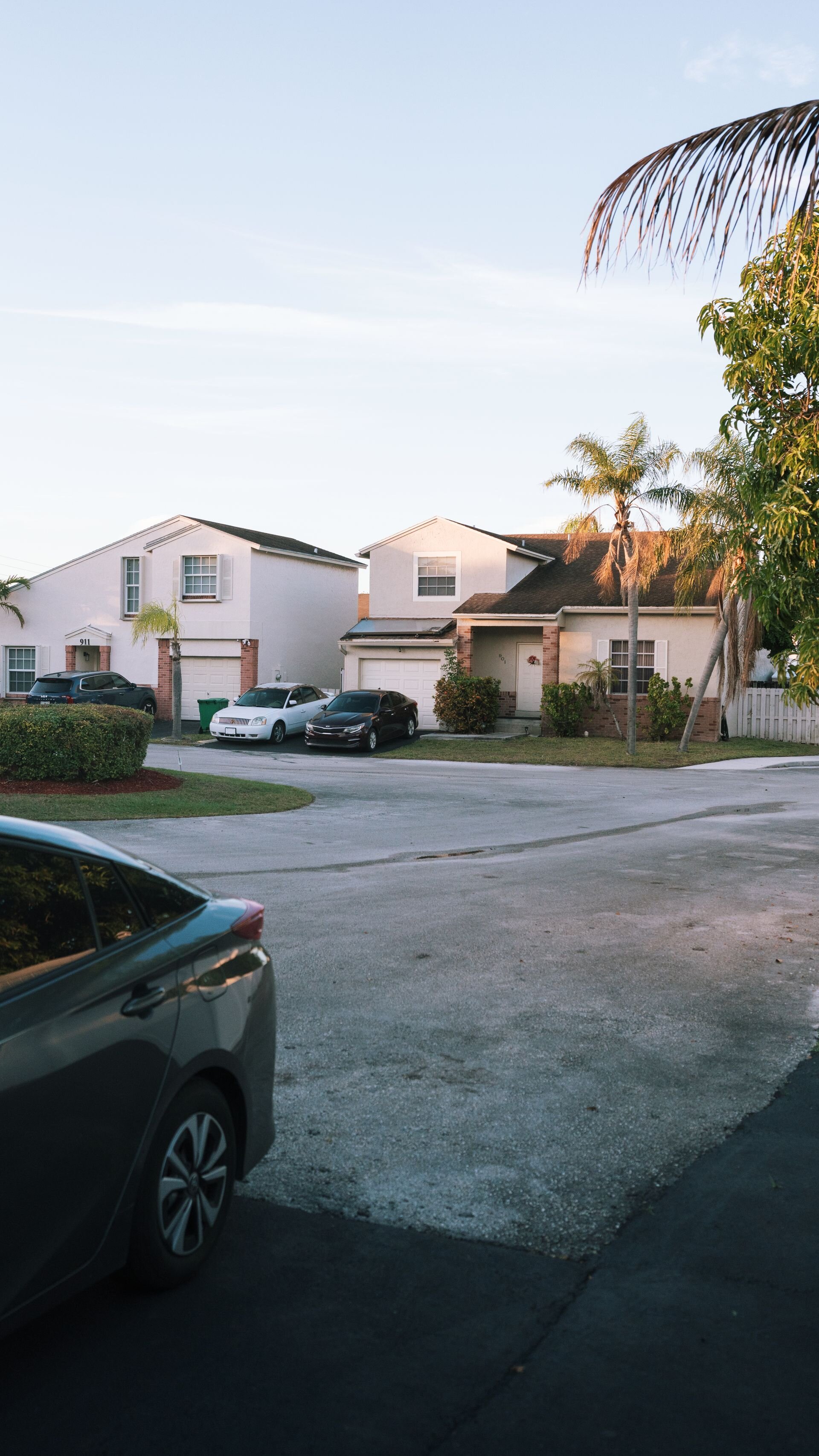 Ordinary Florida neighborhood street with single-family homes, palm trees, and cars in driveways