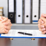 Two hands over divorce agreement trying to discuss how to protect real estate assets during their divorce