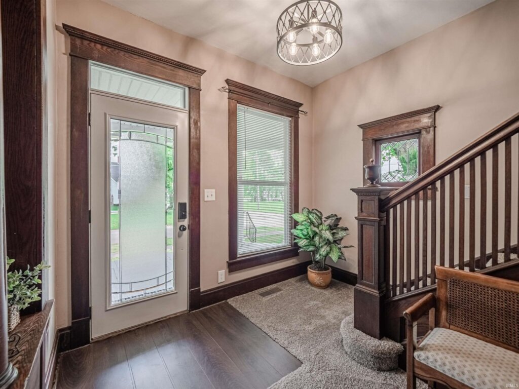 Entryway of a house with character. There's a large staircase and a beautiful front door.