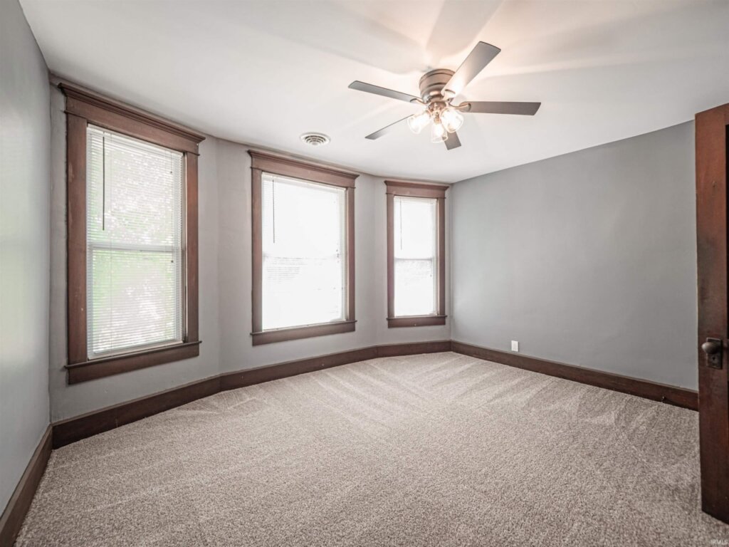 Master bedroom featuring a wall with character and three windows and a ceiling fan.