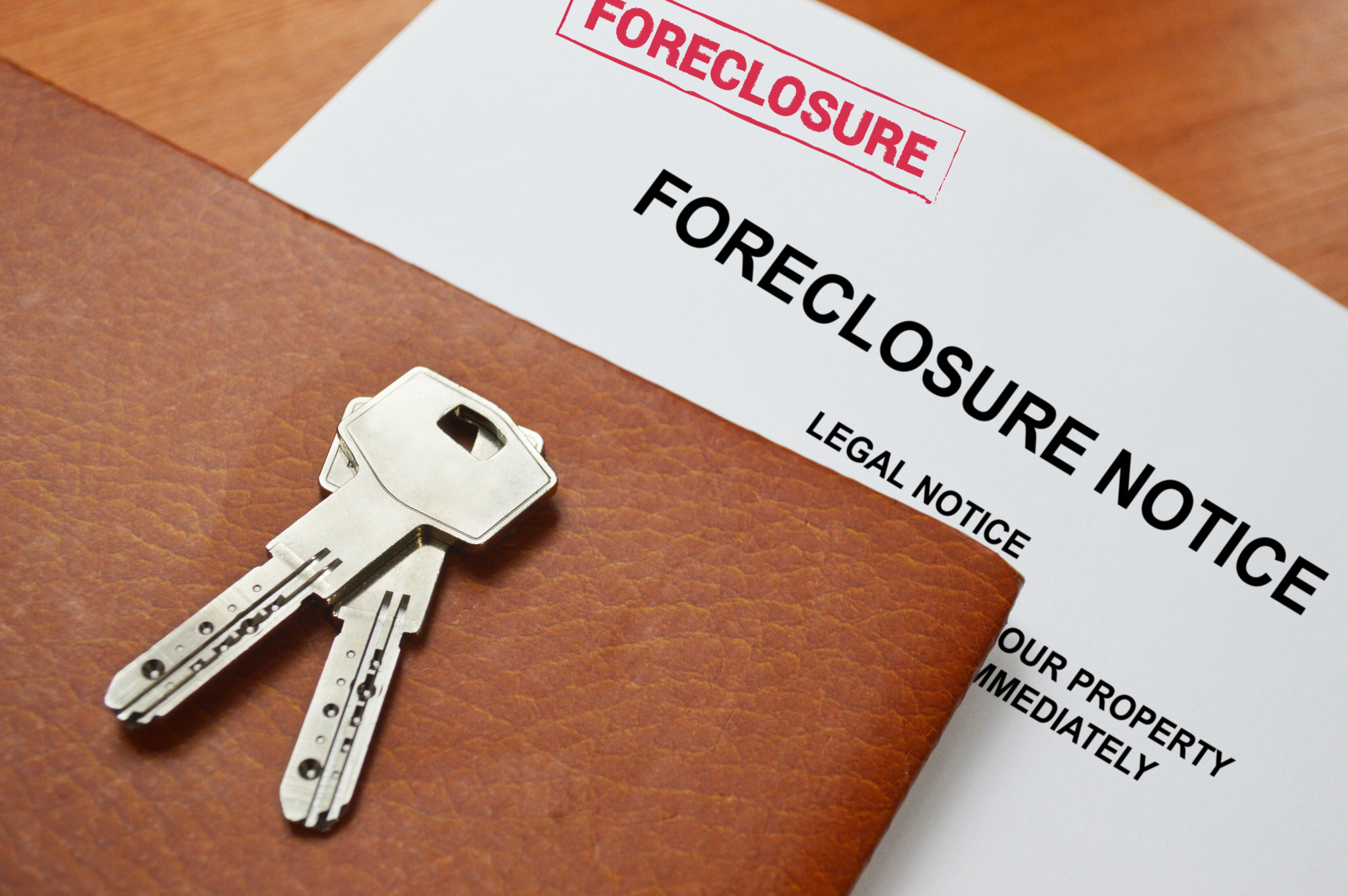 Forclosure notice with a set of house keys beside the notice