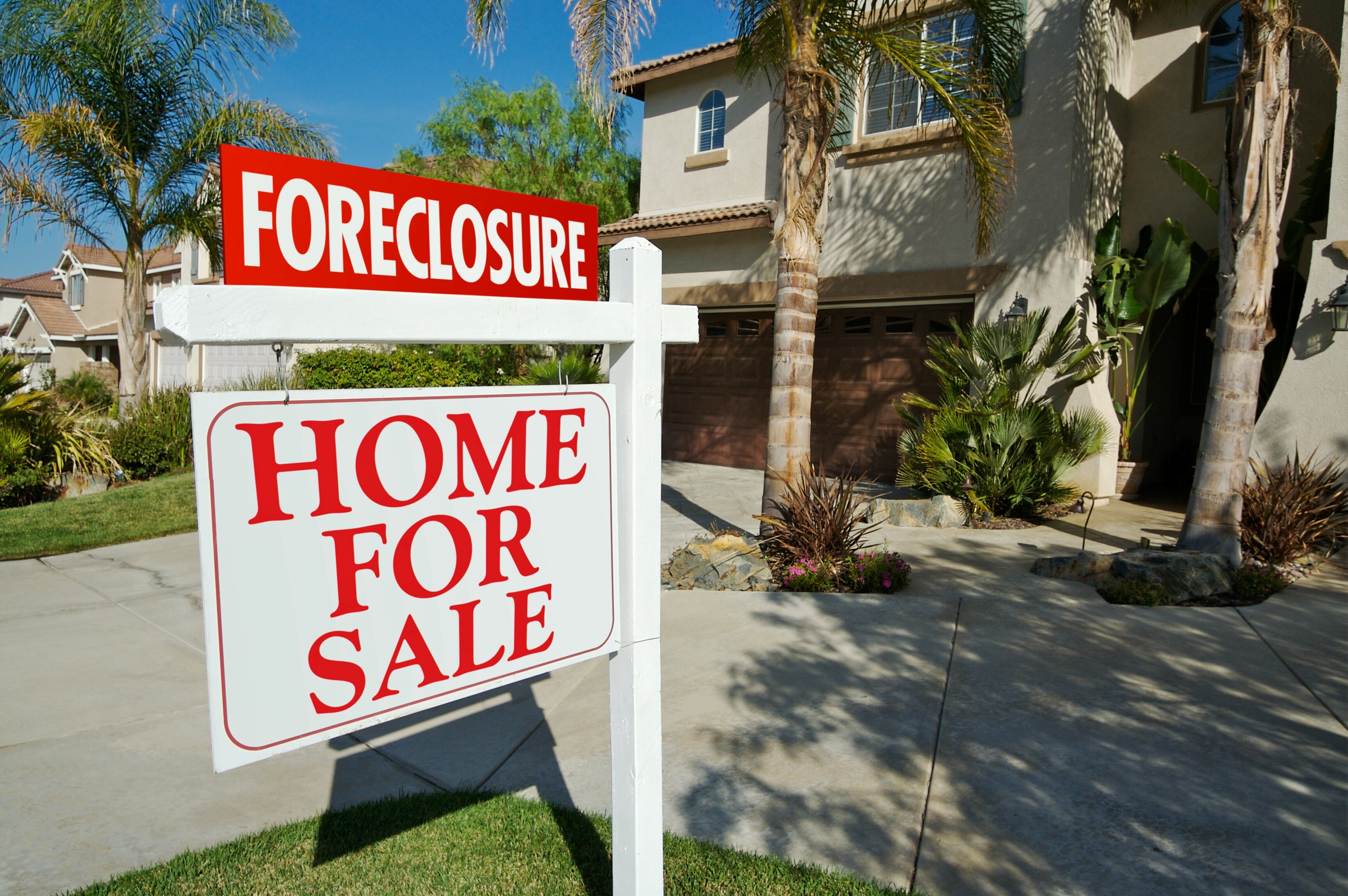 For sale sign in front yard with a foreclosure tag on the sign