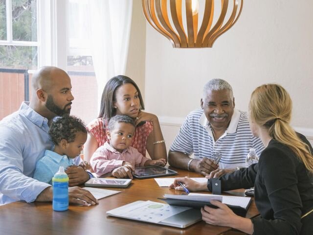 Family meeting with a financial advisor, discussing documents at a table in a well-lit room.

