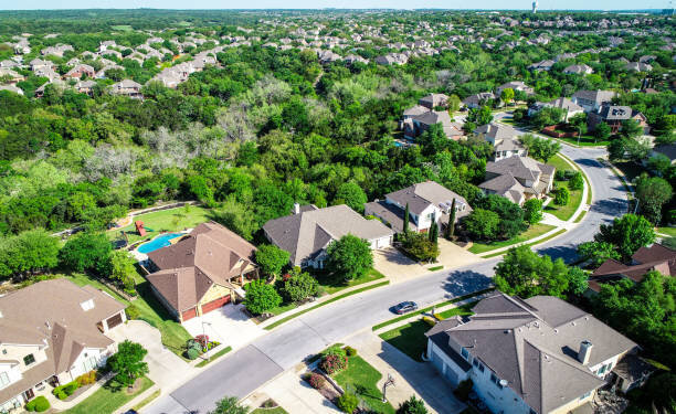 Aerial view of a suburban neighborhood with spacious homes, lush greenery, and winding streets.
