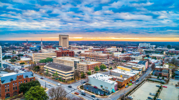 A wintertime view of Greenville, South Carolina, capturing the downtown area under a dramatic cloudy sky with warm lighting highlighting the cityscape.