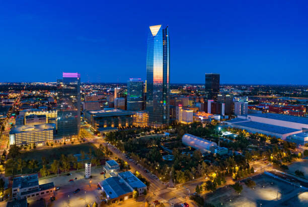 Oklahoma City downtown lit up at night, showcasing the Devon Tower and surrounding urban landscape with glowing streets below.