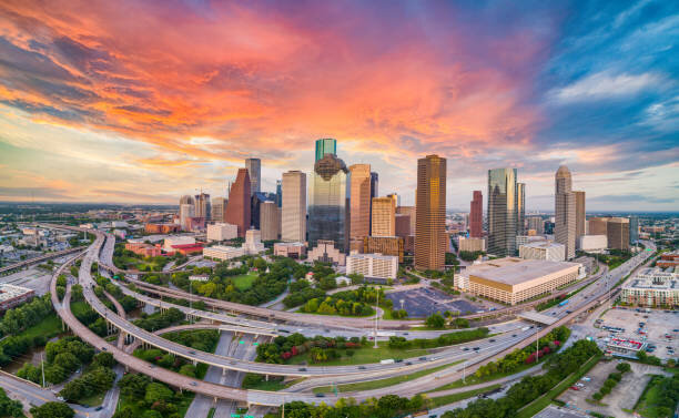 A sweeping aerial view of Houston's iconic skyscrapers under a stunning sunset, with highways weaving through the city.