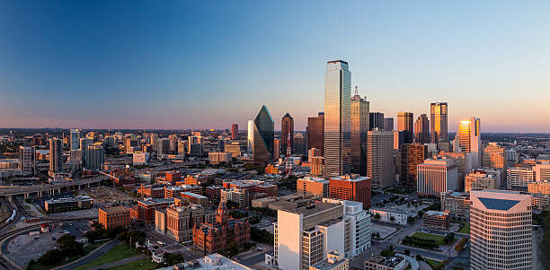 Panoramic view of downtown Dallas during golden hour, with sunlight reflecting off skyscrapers and highlighting the city's urban architecture.