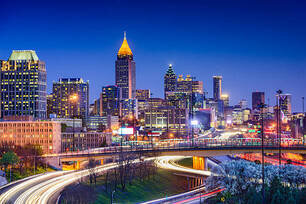 Atlanta skyline at night, featuring glowing skyscrapers, illuminated roads, and vibrant city lights.