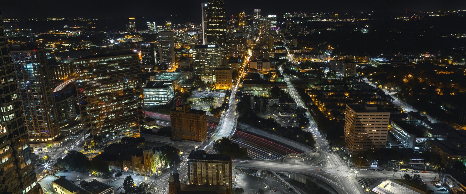 Night cityscape with illuminated buildings and streets in a bustling downtown area.