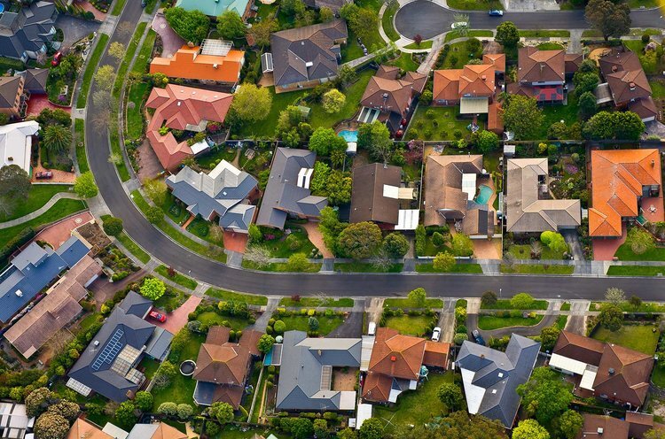 Aerial view of a suburban neighborhood with curved streets and houses surrounded by greenery.
