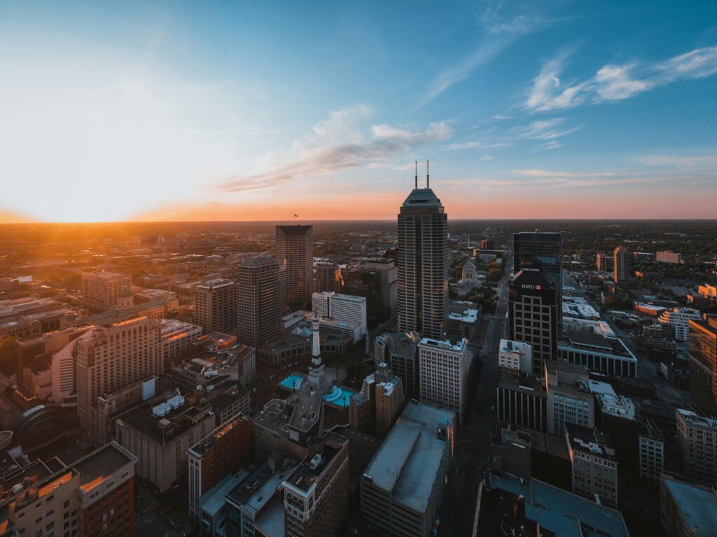 Aerial view of a city at sunset with modern skyscrapers and warm lighting.