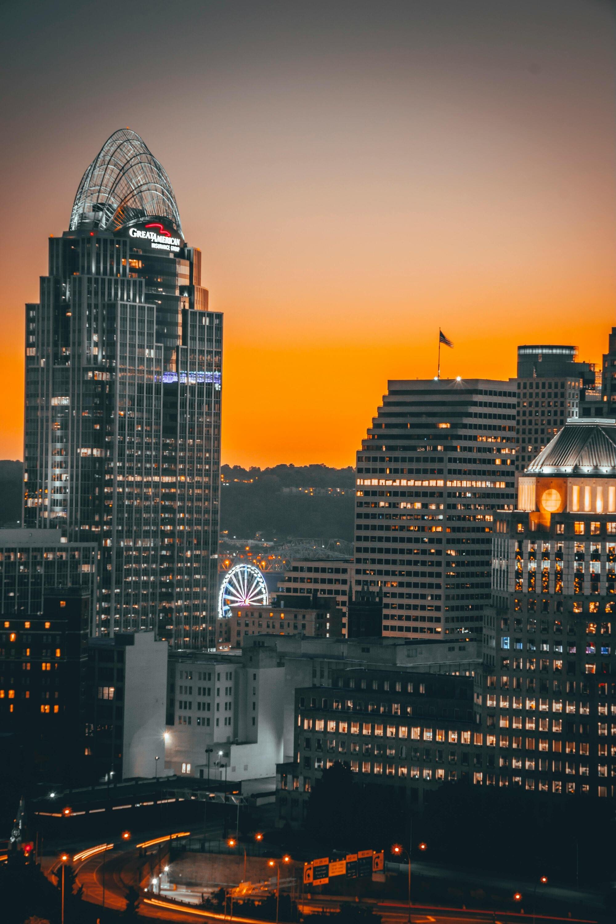 Close-up of Cincinnati's downtown buildings during a vivid orange sunset, with the Great American Tower standing prominently.
