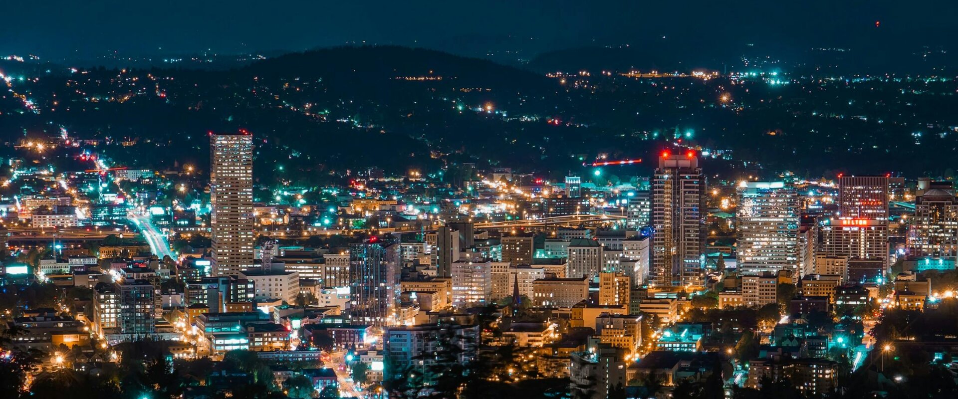Night view of a city with vibrant lights illuminating the skyline and surrounding hills, creating a bustling and lively atmosphere.