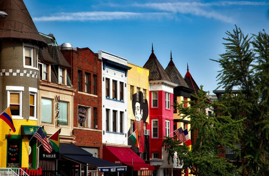Colorful row of historic buildings with vibrant facades and flags on display, set against a clear blue sky.